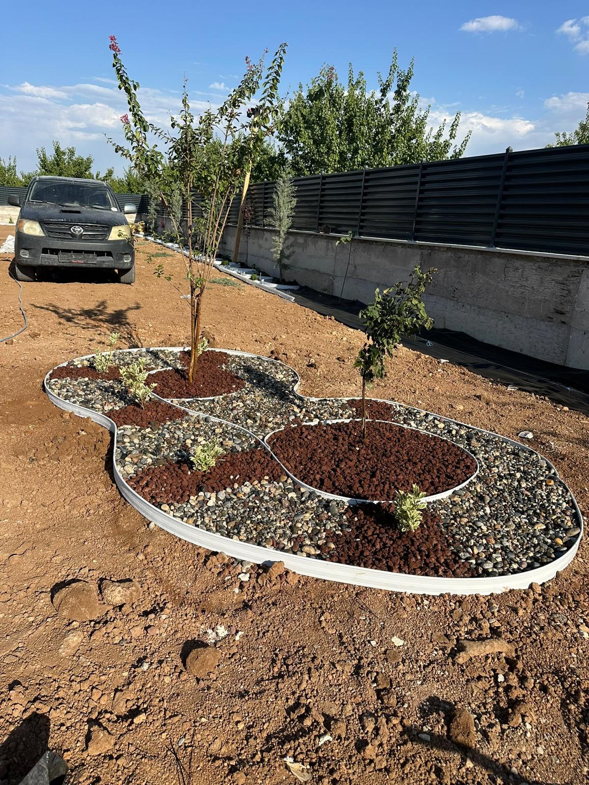 Ağaçlar ve dekoratif taşlarla şekillendirilen bahçe peyzaj alanı